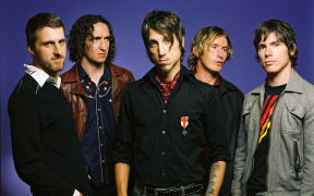 Five men stand in a line looking tough.