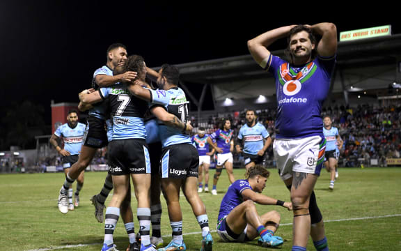 Sharks players celebrate as Josh Curran of the Warriors walks away.