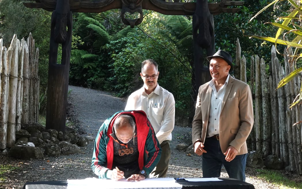 Te Kapotai representative Ned Peita signs the Ruapekapeka Pā Action Plan while DOC Whangārei operations manager Joel Lauterbach and Te Ruapekapeka Trust chairman Pita Tipene look on.