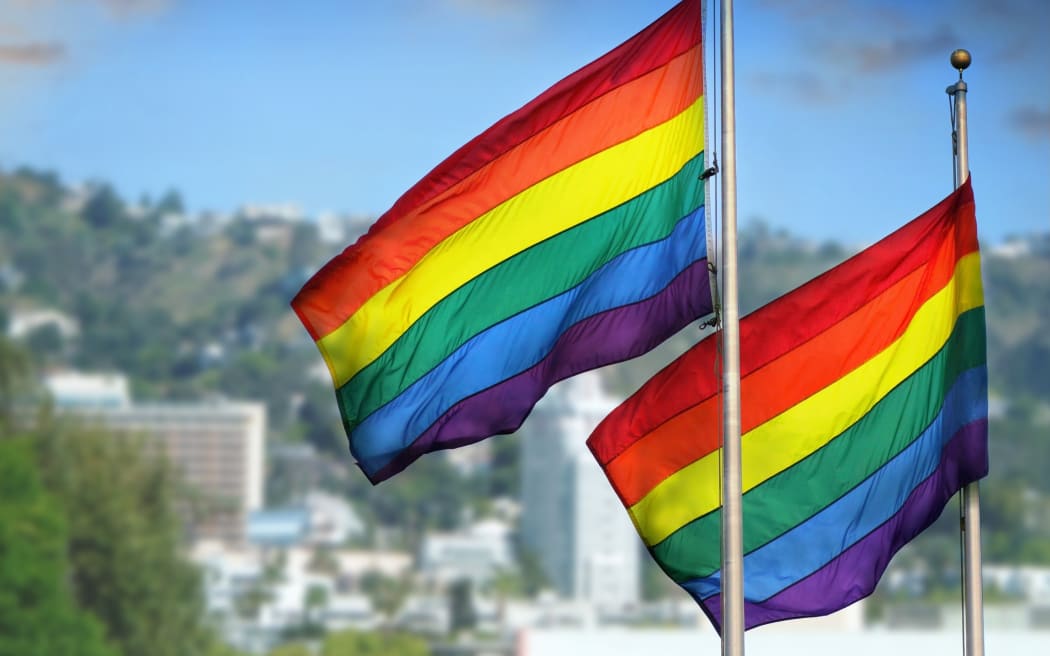 21543261 - a pair of rainbow flags waving in wind against city background of west hollywood, california