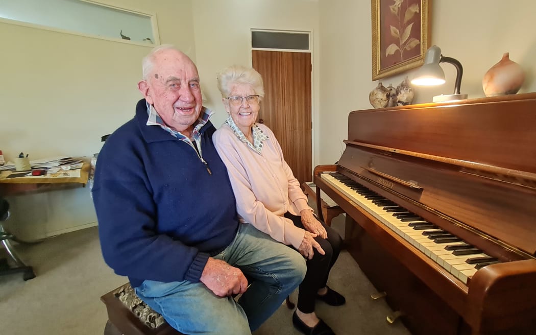 Ian and Pam Buckingham sitting in front of the piano in their home