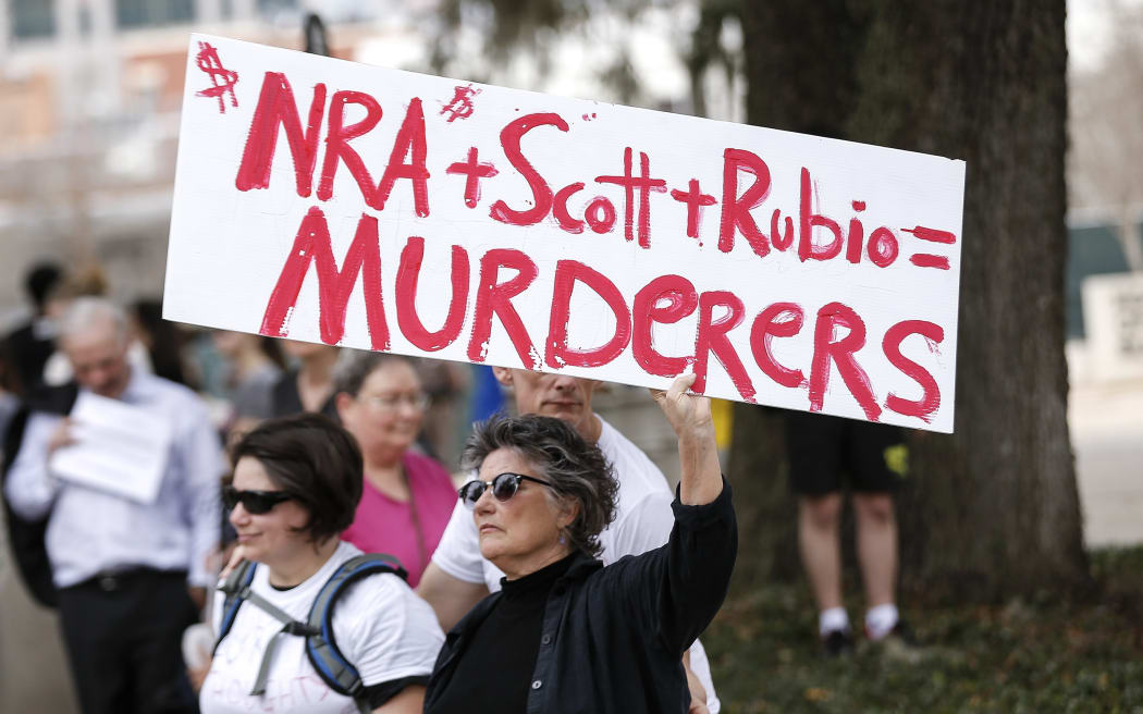 An activist holds up a placard during a rally at the Florida State Capitol building to address gun control on February 21, 2018 in Tallahassee, Florida.
