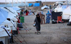 An Iraqi woman who fled violence in the northern city of Tal Afar walks through the Bahrka camp, in the autonomous Kurdish region.