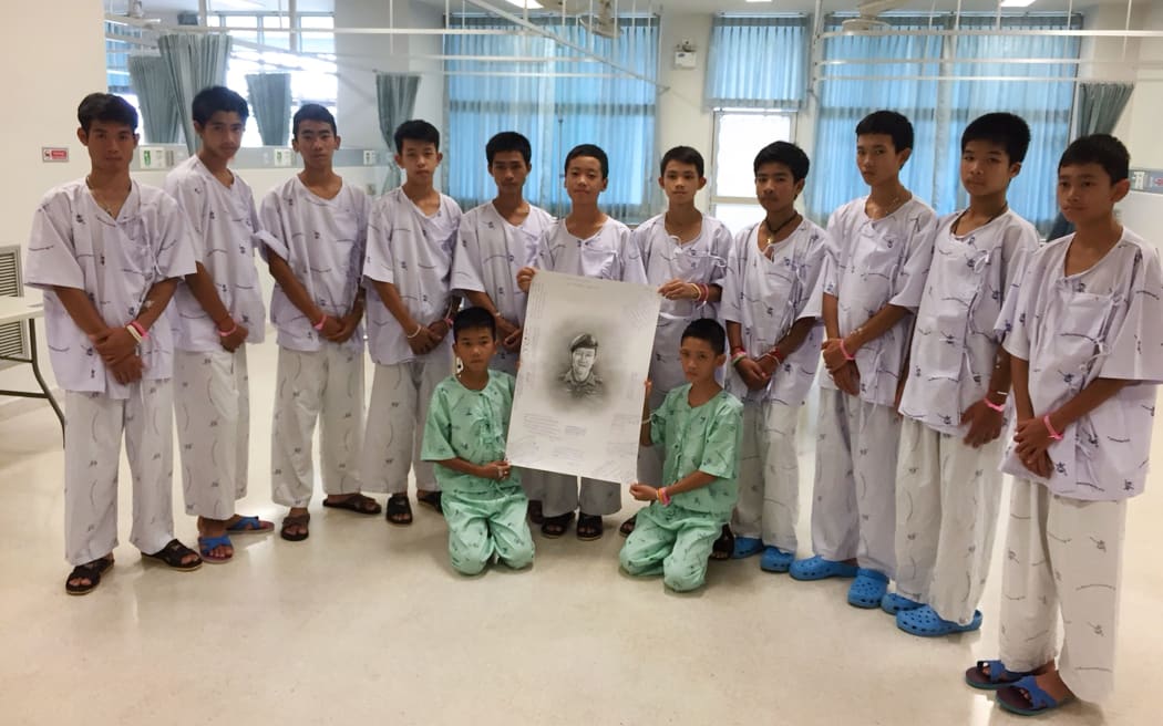 This handout photo released by the Ministry of Health shows members of the rescued "Wild Boars" football team at hospital in Chiang Rai province posing after writing messages on a drawing of former Navy SEAL diver Saman Kunan.