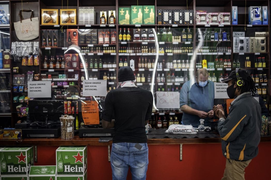A customer buys alcohol while another one sanitises his hands at a liquor shop in Hillbrow, Johannesburg. South Africa moved into level two of a five-tier lockdown on August 18, 2020, to continue efforts to curb the spread of the COVID-19. Under level two liquor and tobacco sales will resume.