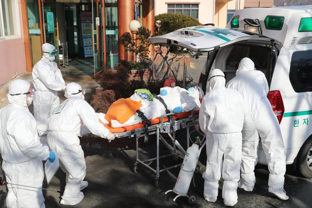Medical workers wearing protective gear transfer a suspected coronavirus patient  to another hospital from Daenam Hospital where a total of 16 infections have now been identified.