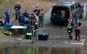 Law enforcement officers use an underwater robotic camera to search the water around the Pejepscot Boat Ramp on the Androscoggin River where the suspect being searched for in connection with two mass shootings abandoned his vehicle on 27 October, 2023 in Lisbon, Maine.