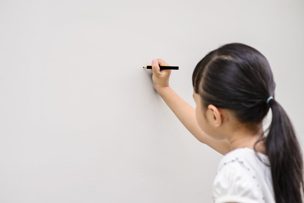 Asian girl writing on wall