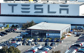 File photo. In an aerial view, new Tesla cars sit in a parking lot at the Tesla factory on October 19, 2022 in Fremont.