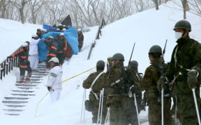 Firefighters carry a survivor they rescued from the site of the avalanche.