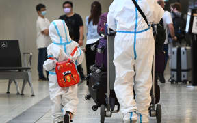 International travellers wearing personal protective equipment (PPE) arrive at Melbourne's Tullamarine Airport on November 29, 2021 as Australia records it's first cases of the Omicron variant of Covid-19.
