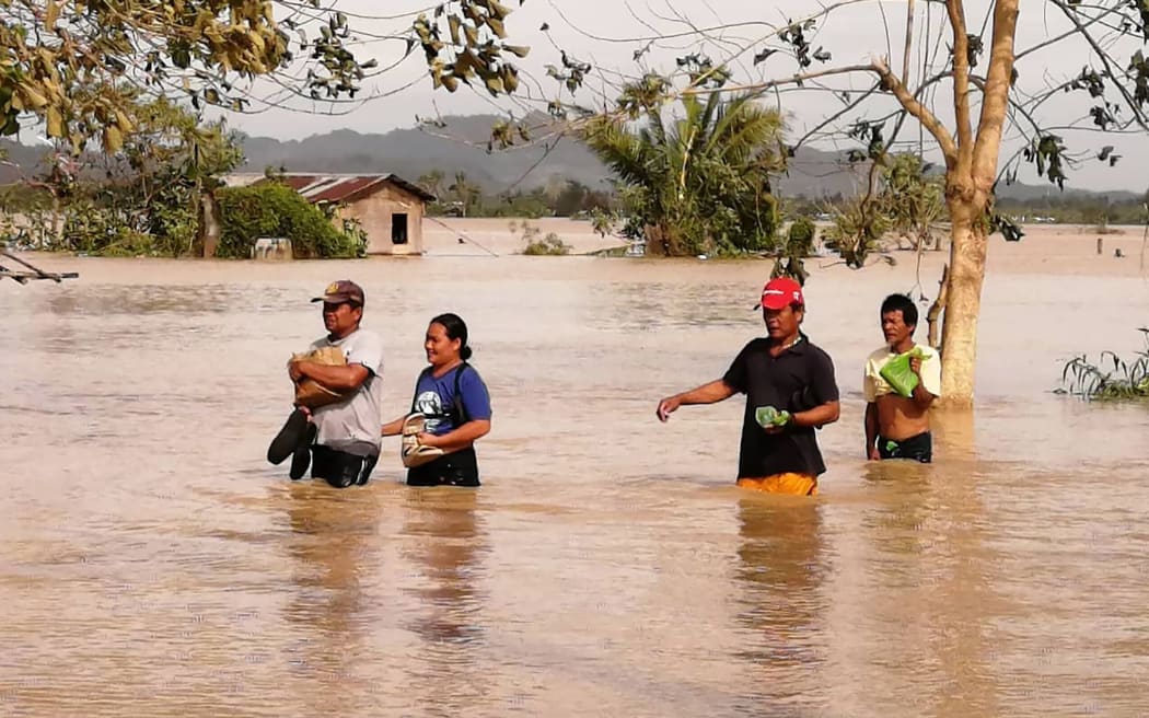 Residents wade through a flooded highway, caused by heavy rains due to typhoon Phanfone, in Ormoc City, Leyte province in central Philippines.