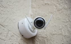 A security camera, high on the wall of a building.