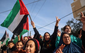 Displaced Palestinians waving national flags cheer as they return to Rafah in the southern Gaza Strip on January 19, 2025, hours after a ceasefire deal in the war between Israel and the Palestinian militant group Hamas was expected to be implemented. (Photo by Eyad BABA / AFP)