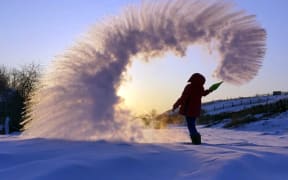In this handout photo taken on Tuesday, Feb. 5, 2019, a woman throws boiling water into the freezing air as its instantly condenses into an elaborate pattern of ice crystals in Irkutsk, Russia .