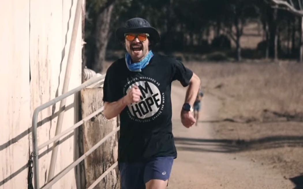 Ultra Runner Sam runs through a gate on a dusty road during the 2023 Dead Cow Gully race in Australia.