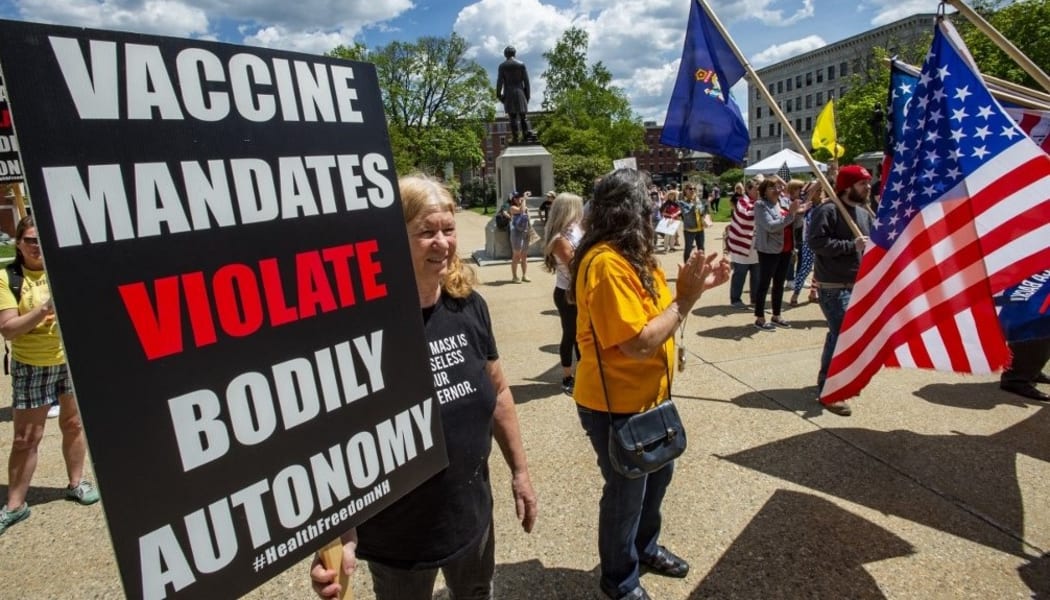 Rally goers hold signs protesting vaccines at the "World Wide Rally for Freedom", an anti-mask and anti-vaccine rally, at the State House in Concord, New Hampshire, May 15, 2021.