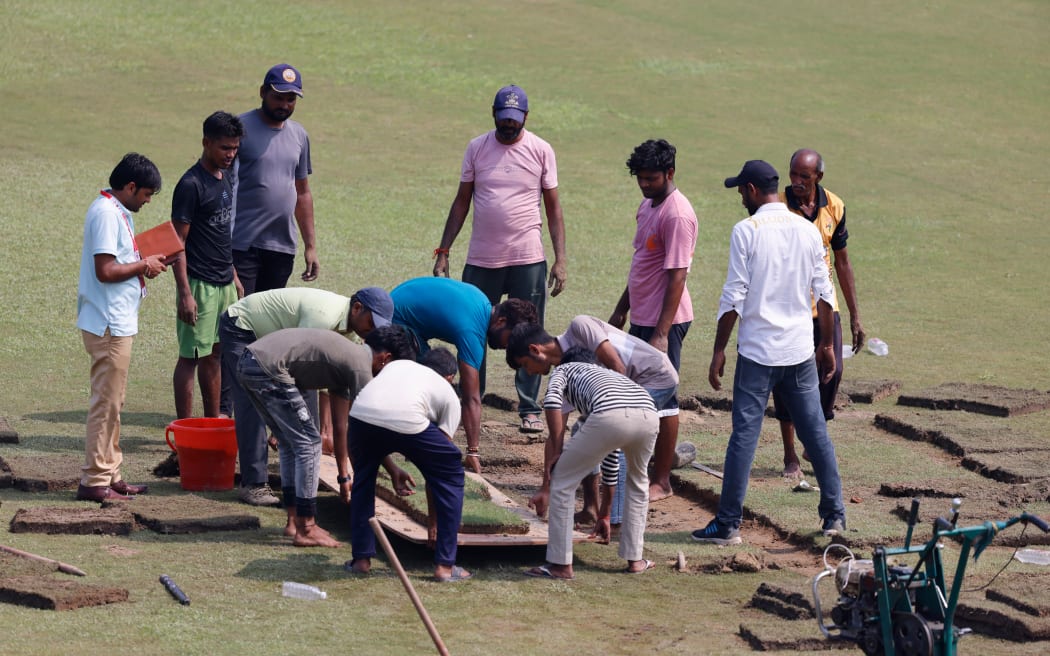 Groundsmen prepare the field with artificial grass before the start of the one-off Test cricket match between Afghanistan v New Zealand,  Greater Noida, 2024.