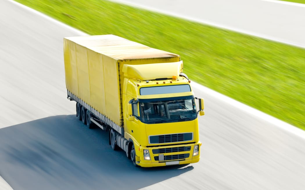 10069448 - vivid yellow truck in motion under bright sun on a highway