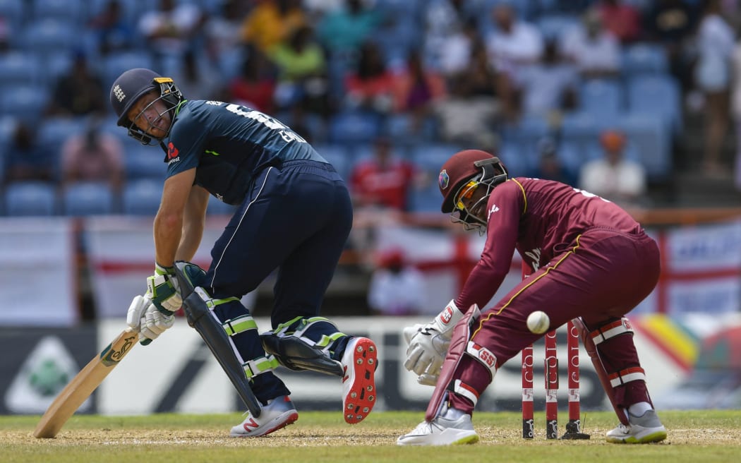 Jos Buttler (L) of England hits past Shai Hope (R) of West Indies during the 4th ODI between West Indies and England at Grenada National Cricket Stadium.