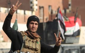 A member of Iraq's elite counter-terrorism service flashes the "V" for victory sign.