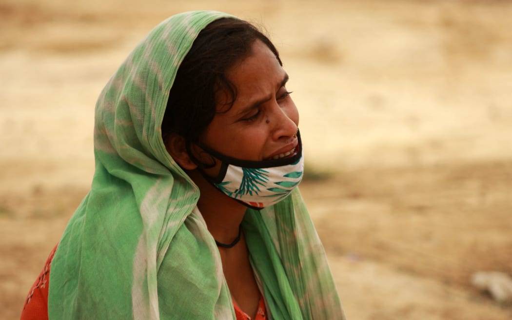 A relative mourns after the burial of a woman who died of Covid-19, at a graveyard, on March 30, 2021 in New Delhi.