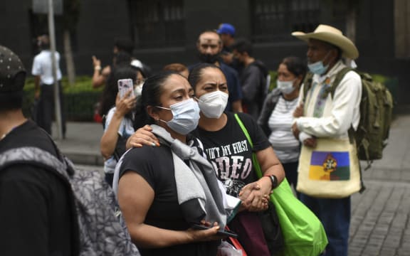 People remain in the street in Mexico City on September 19, 2022 after a powerful earthquake struck western Mexico on Monday, shaking buildings hundreds of miles away in Mexico City on the anniversary of two major tremors in 1985 and 2017.