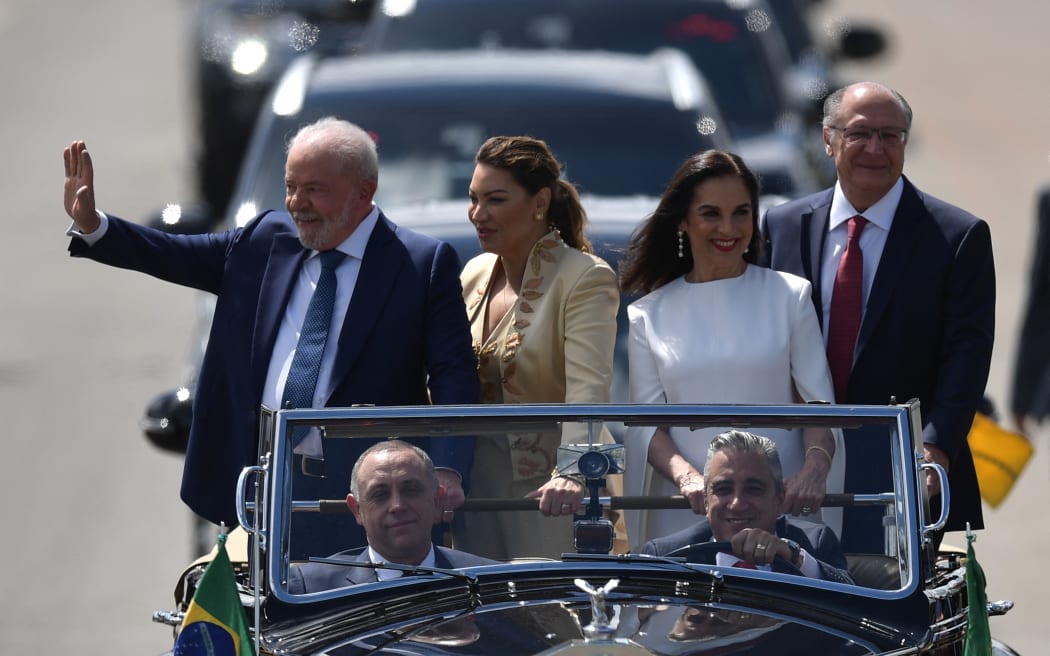 Brazil's President-elect Luiz Inacio Lula da Silva (left) waves to supporters, accompanied by his wife Rosangela da Silva (second from left), his Vice-President-elect Geraldo Alckmin (right), and his wife, Maria Lucia Ribeiro Alckmin, on their way to the National Congress for their inauguration ceremony, in Brasilia, on January 1, 2023.