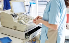 Retail worker at cash register.