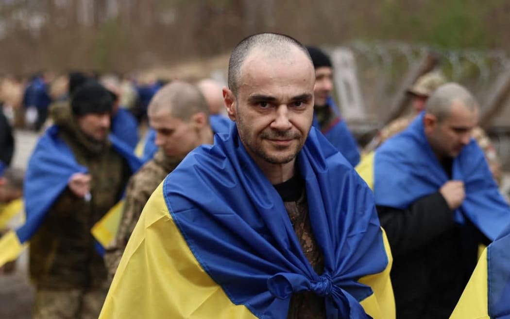 This handout photograph published in the official Telegram channel of Ukrainian President Volodymyr Zelensky on March 19, 2025, shows some of the 175 Ukrainian prisoners of war wrapped with national flags, following an exchange at an undisclosed location, amid the Russian invasion in Ukraine. The Russian defence ministry said it had handed over 175 Ukrainian prisoners of war and 22 "seriously wounded" Ukrainian captives while Kyiv had delivered 175 Russian prisoners in return. Prisoner swaps and the exchange of remains of killed soldiers is one of the only areas of cooperation between the warring countries since the Kremlin launched the Russian invasion of Ukraine in early 2022. (Photo by Handout / Telegram / @Volodymyr Zelensky / AFP) / RESTRICTED TO EDITORIAL USE - MANDATORY CREDIT "AFP PHOTO / OFFICIAL TELEGRAM CHANNEL OF UKRAINIAN PRESIDENT VOLODYMYR ZELENSKY " - NO MARKETING NO ADVERTISING CAMPAIGNS - DISTRIBUTED AS A SERVICE TO CLIENTS