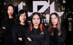 A group of women look at the camera with folded arms. They are all wearing black team hoodies with "E BLACKS" on them in white lettering.