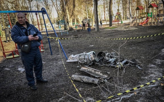 A man stands next to remains of a missile in the eastern Ukraine city of Kharkiv on February 24, 2022, as Russian armed forces launched a military invasion of Ukraine.