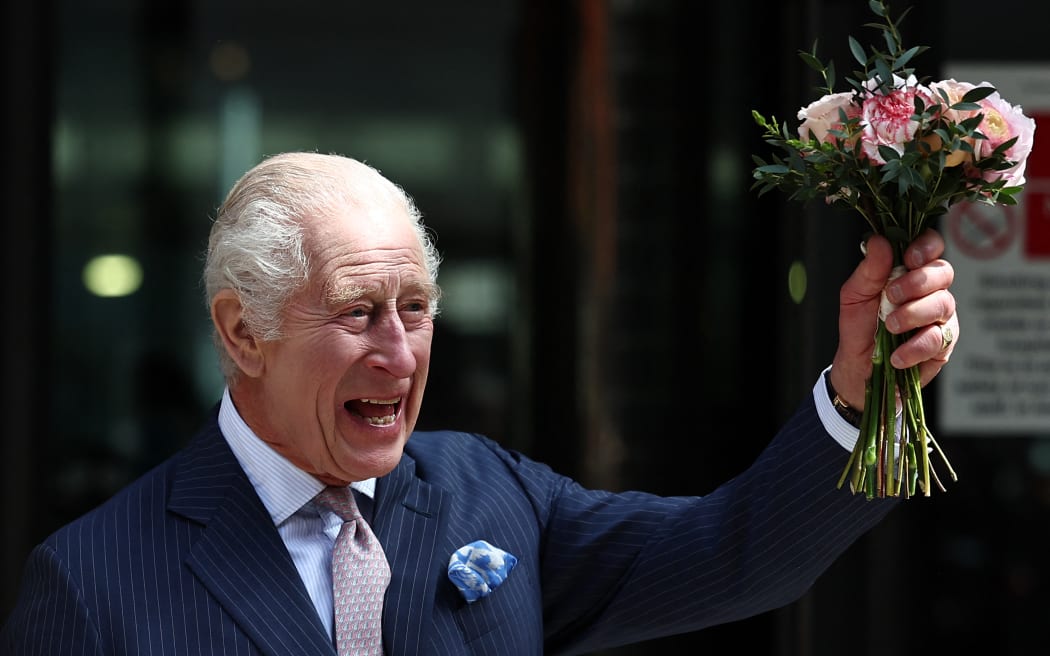 Britain's King Charles III, holding a bunch of flowers, waves to crowds after to visit to the University College Hospital Macmillan Cancer Centre in London on April 30, 2024. Charles is making his first official public appearance since being diagnosed with cancer, after doctors said they were "very encouraged" by the progress of his treatment. (Photo by HENRY NICHOLLS / AFP)