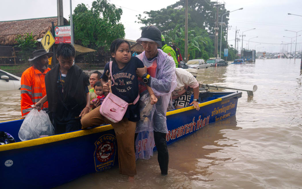 A child is helped off a boat after being rescue in flood waters in Hat Yai in Thailand's southern Songkhla province on November 26, 2025.