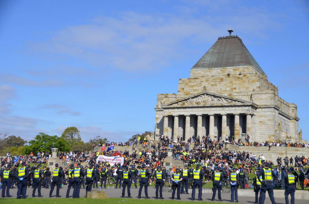 Demonstrators gather during an anti-lockdown protest and police officers stand guard in Melbourne, Australia.