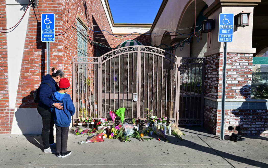 Inez Arakaki comforts her son Zachary as they visit a makeshift memorial site in front of the Star Dance Studio in Monterey Park, California, on January 23, 2023, after a mass shooting at the venue.