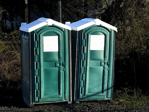 Two green portable toilets outdoors.