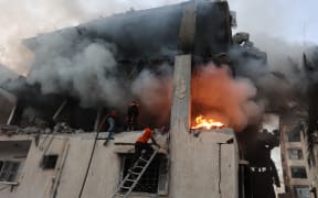 Civil defence personnel search a burning house targeted by Israeli airstrikes in Gaza City, on November 22, 2025. Gaza's civil defence agency said 21 people were killed and dozens more wounded in multiple Israeli air strikes on the Palestinian territory on November 22.