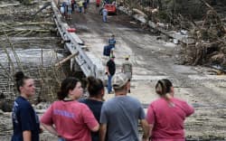 People look on as law enforcement and volunteers continue to search for missing people near Camp Mystic, the site of where at least 20 girls went missing after flash flooding in Hunt, Texas, on July 5, 2025. Rescuers were on Saturday searching for more than 20 girls missing from a riverside summer camp in the US state of Texas, after torrential rains caused devastating flooding that killed at least 27 people — with more rain on the way. “So far, we’ve evacuated over 850 uninjured people, eight injured people and have recovered 27 deceased fatalities at this time. Of these 27, 18 are adults, nine are children,” said Kerr Country Sheriff Larry Leitha on July 5. (Photo by RONALDO SCHEMIDT / AFP)