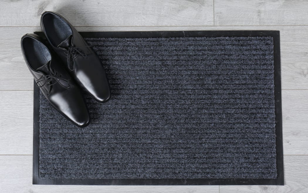 Door mat and shoes on floor, top view. Space for text