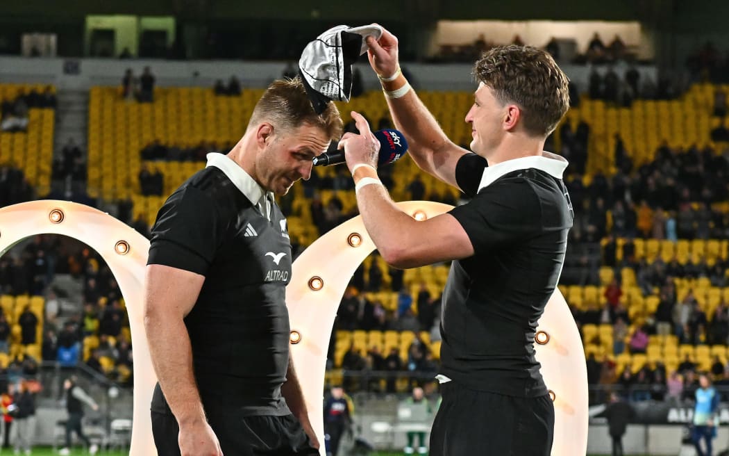 New Zealand's Beauden Barrett presents Sam Cane with a cap for 100 games.