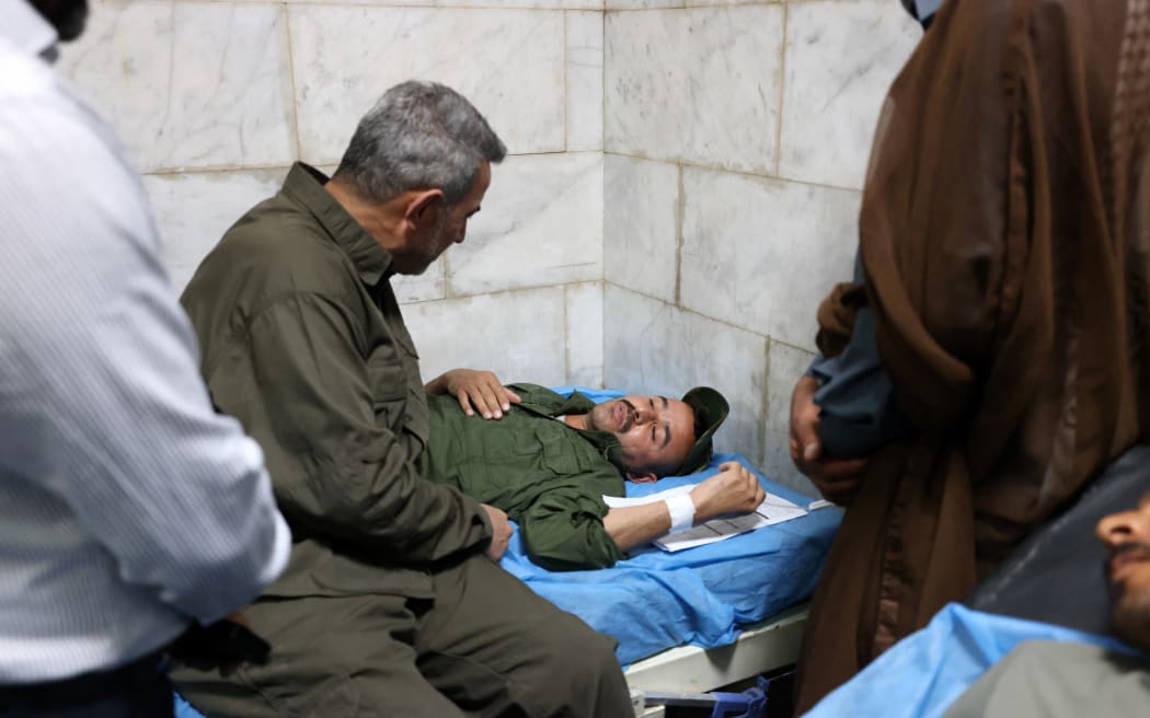 Abu Fadak Al-Mohammedawi (left), the chief of staff of Iraq’s Popular Mobilization Forces (PMF) visits Iraqi military personnel at a hospital in Hilla in the central province of Babylon after they were wounded in an overnight blast in an Iraqi military base housing a coalition of pro-Iranian armed groups, on April 20, 2024.