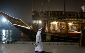 An Emirati man walks past a restaurant boat adorned for the Muslim holy month of Ramadan.