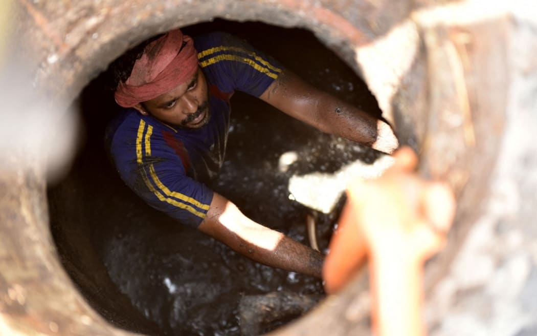 A worker employed by the KWA working inside a manhole near Pettha to clear a block in the sewage line. The irony is that even as "Bandicoot" the sewage cleaning robot developed by Kerala, struggles to find users in the home state, the robot has replaced manual scavengers in five other states with Gujarat being the latest one. The Times of India/Rakesh Nair (Photo by Rakesh Nair / The Times of India / The Times of India via AFP)
