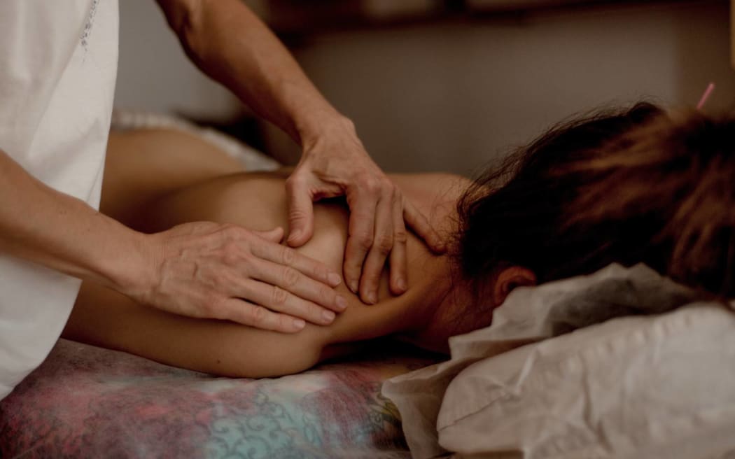 Close-up of hands of a masseur massaging back of a young woman, traditional chinese medicine.