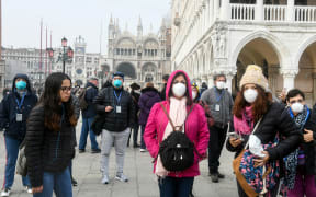 Tourists wearing protective masks visit Venice on 25 February 2020, during the usual period of the Carnival festivities which were cancelled after an outbreak of the Covid-19 coronavirus.