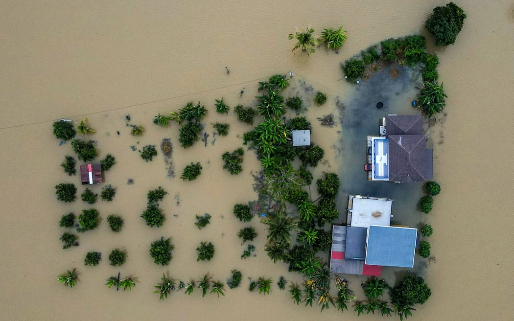 An aerial view shows a home surrounded by flood waters in Kangar in northern Malaysia's Perlis state on November 27, 2025.