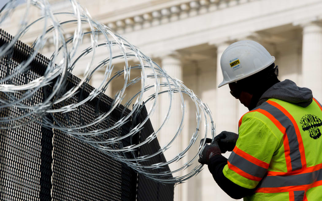 WASHINGTON, DC - JANUARY 15: Work crews install razor wire on top of the fencing surrounding the US Capitol ahead of the inauguration on January 15, 2021 in Washington, DC.