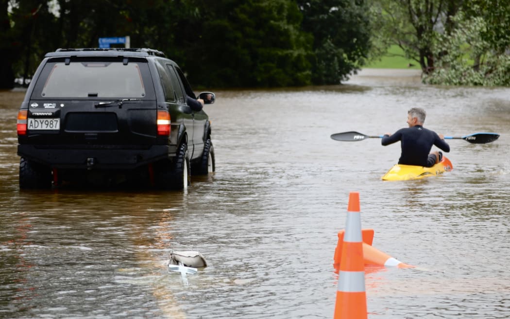 Residents navigate through flooded roads just before Waimauku, Auckland.