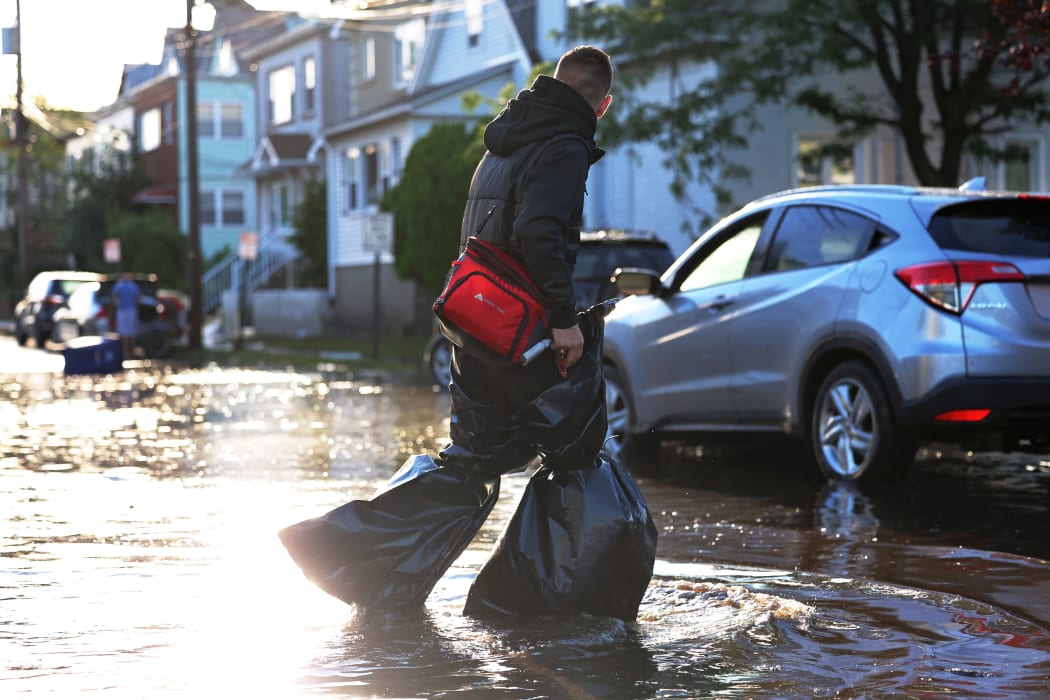 A man uses garbage bags to keep his pants and feet dry as he crosses a flooded street in Passaic City after Cyclone Ida.